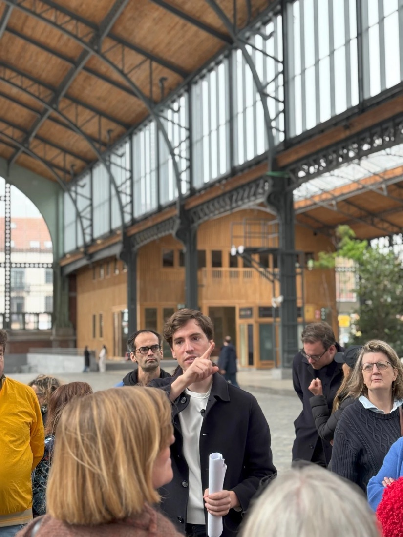 Frederik Ceulemans leading a group walk under the iron and glass roof of a Brussels market hall